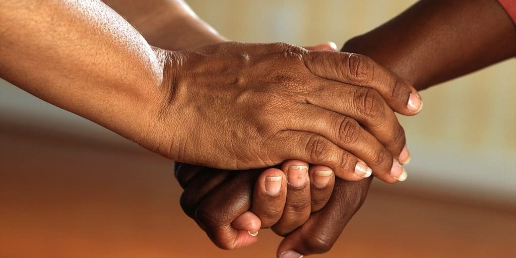 A person holding another's hand with both of their own. 