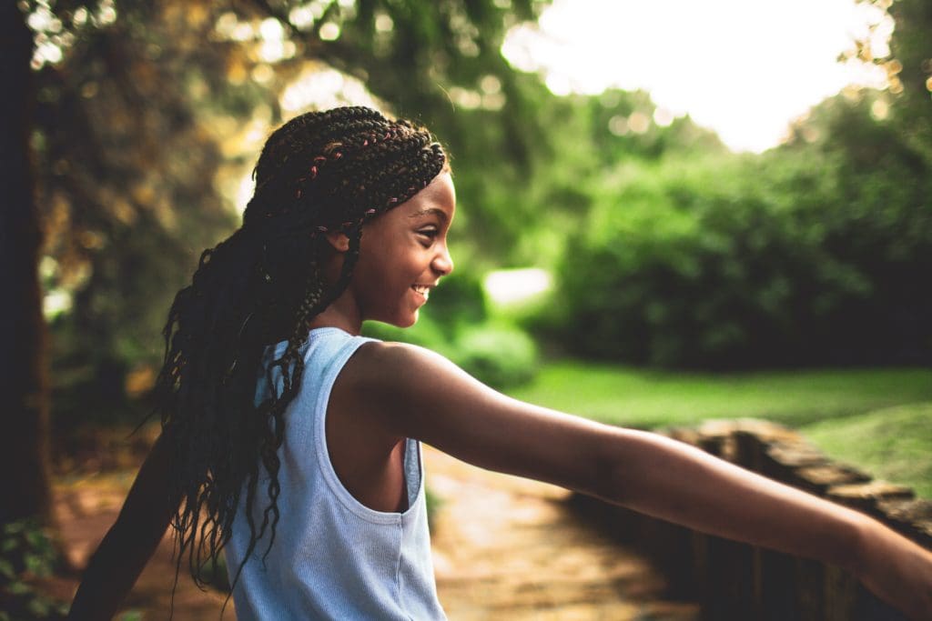 A young girl smiling and playing outside.