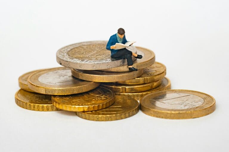 A man reading a book sitting on top of coins.